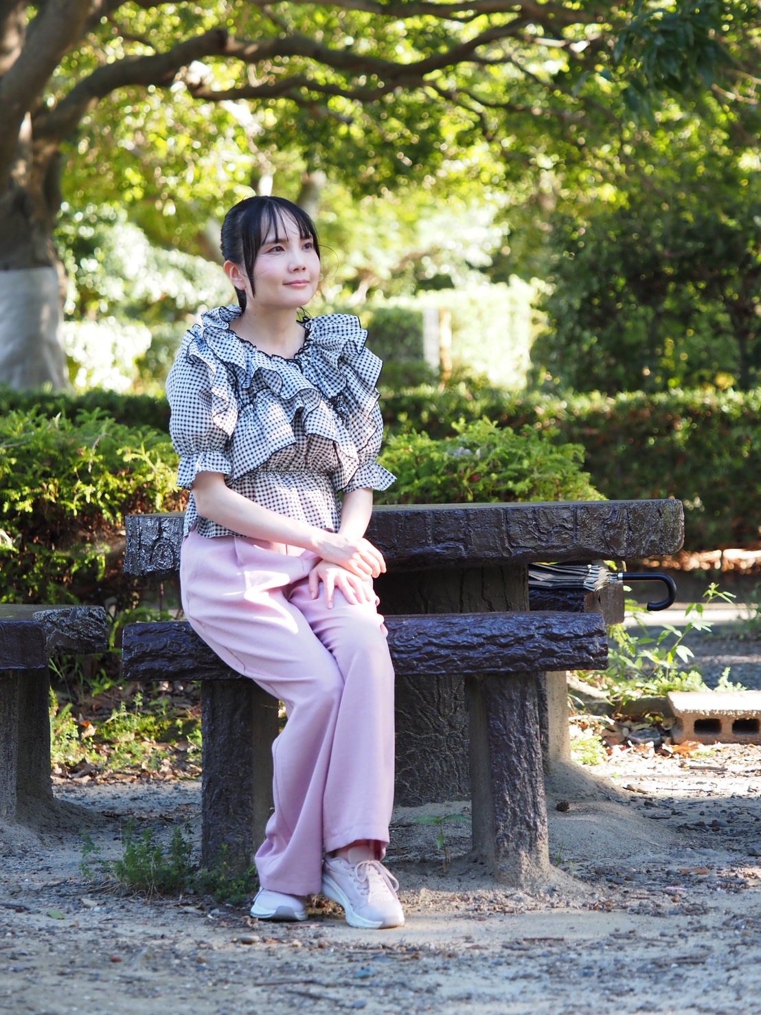 緑の木々に囲まれたベンチに座る藤林あみ